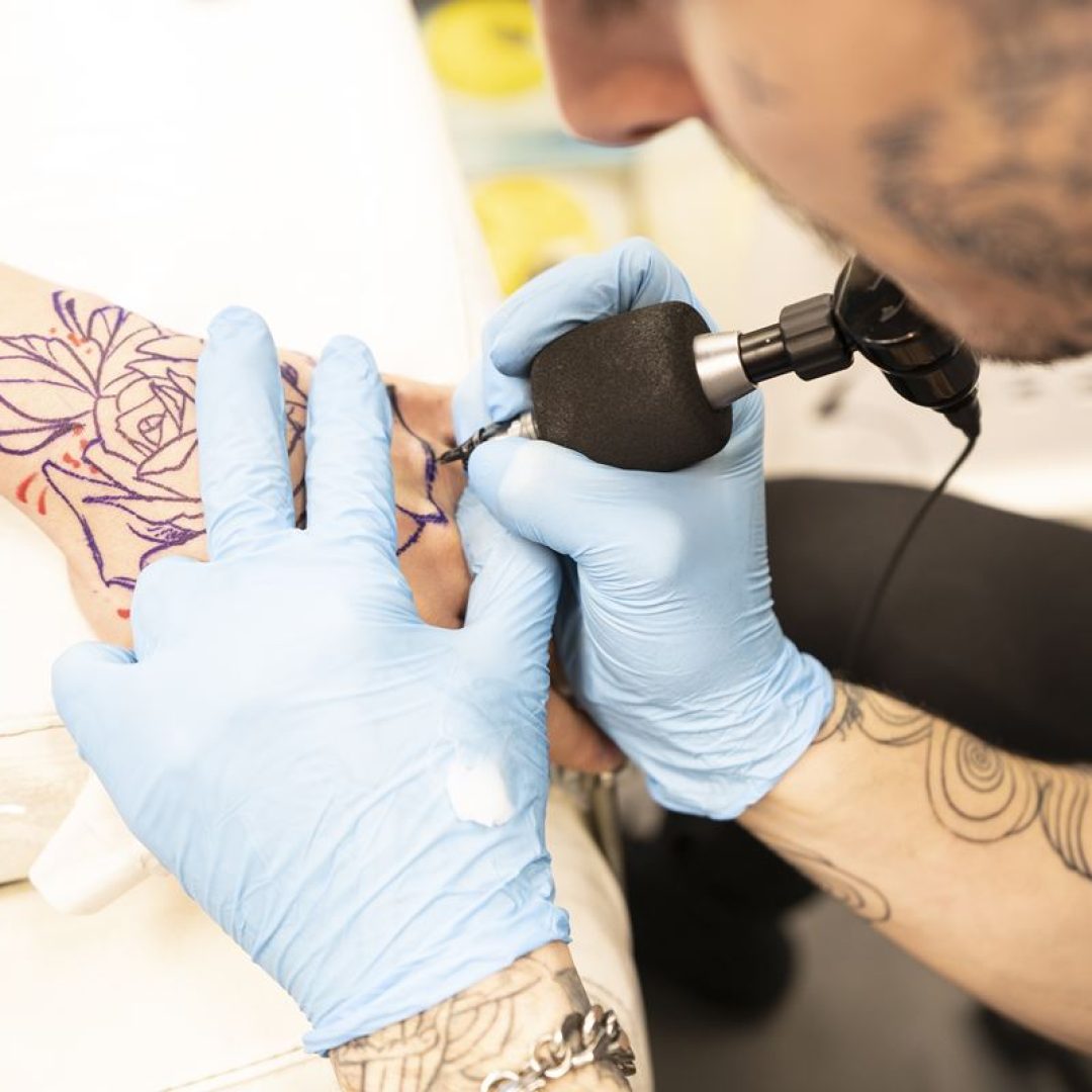 Tattoo artist tattoing hand